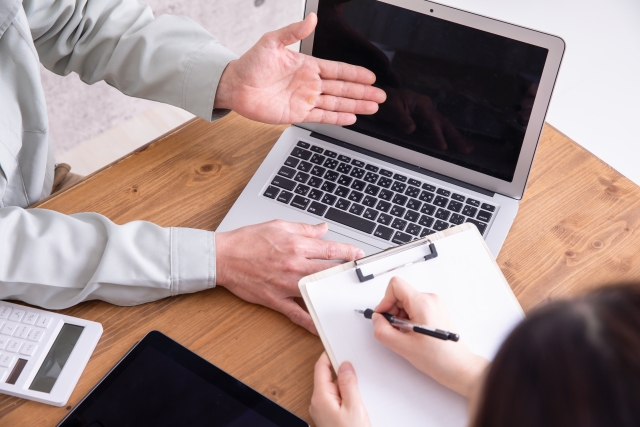 ノートパソコンを使いながら説明を受けメモを取る打ち合わせの様子